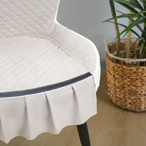 Housse de chaise matelassée beige avec jupe à volants, détail de protecteur de chaise.