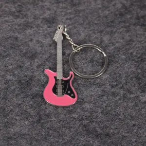 Primer plano de un llavero con forma de guitarra eléctrica rosa sobre fondo gris