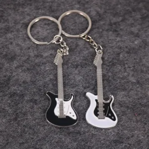 Primer plano de llaveros con forma de guitarra eléctrica blancos y negros sobre fieltro