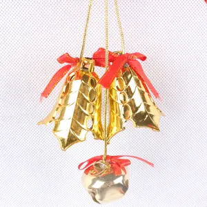 Detail of hanging gold Christmas bell ornaments with red bows and holly leaf design