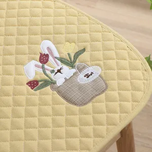 Nahaufnahme des gelben gesteppten Stuhlkissens mit niedlicher Hasen- und Tulpenstickerei.