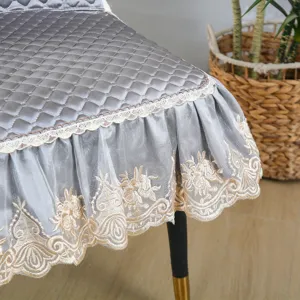 Détail de housse de chaise matelassée grise, jupe en dentelle florale, coussin antidérapant