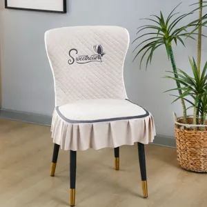 Vue détaillée de la housse de chaise matelassée beige avec jolie jupe à volants et broderie.