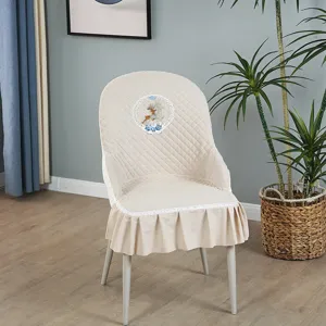 Vue detaillee de la housse de chaise matelassee beige avec broderie de cerf et de dentelle.