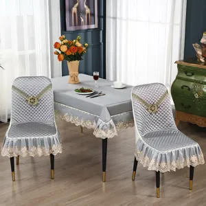 Detailaufnahme grauer, gesteppter Esszimmerstuhlbezüge und Tischdecke mit edler Spitzenstickerei.