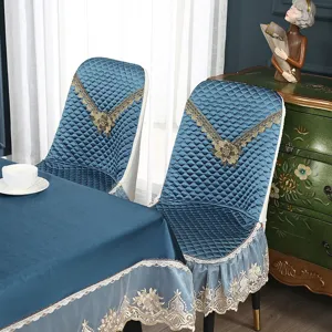 Detailaufnahme des gesteppten blauen Stuhlbezugs und der Tischdecke mit eleganter Spitzenstickerei.