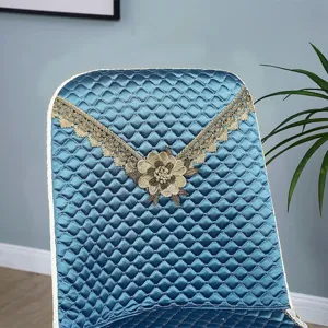 Quilted dining chair cover with elegant lace trim and embroidered flower for home decoration detail.