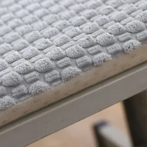 Close-up of grey plush chair cushion, showing textured square fleece fabric details.