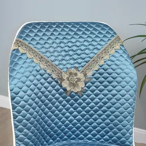 Blue quilted dining chair cover detail, elegant lace trim and floral accent for home use.