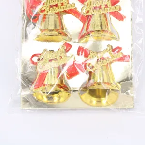 Close-up of gold Christmas bells with red bows and Merry Christmas signs in packaging