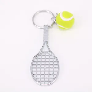 Detalle de un llavero de mini raqueta de tennis plateada con una pelota de tenis verde