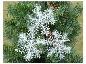 Detail view of white plastic snowflake ornaments hanging on green Christmas tree branches