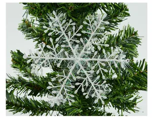Close-up of a white iridescent snowflake ornament on a green Christmas tree branch