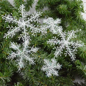 White plastic snowflake ornaments with glitter texture on Christmas tree branches