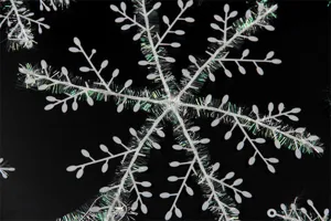 Macro view of Christmas snowflake ornament with iridescent tinsel detail.