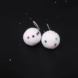 Primer plano de bolas de nieve navideñas de espuma blanca con estrellas de colores sobre negro.