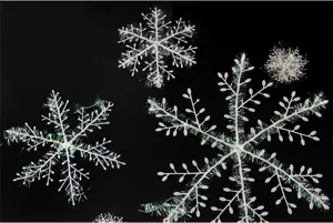 Detailed view of white plastic snowflakes with iridescent tinsel on black background