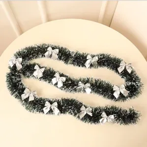 Detail view of dark green Christmas tinsel garland with white tips and silver bows