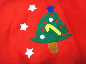 Detailed shot of a green felt tree applique on a small 60cm red Christmas tree skirt