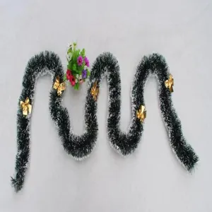 Detailed view of dark green Christmas tinsel garland with white edges and gold bows