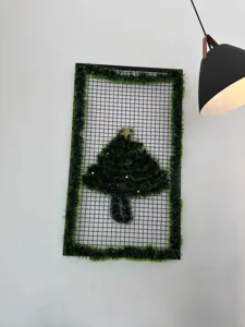 Dark green Christmas tinsel garland decorating a black metal grid on a white wall