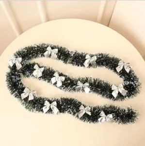 Dark green Christmas tinsel garland with white tips and elegant silver bows for tree decor