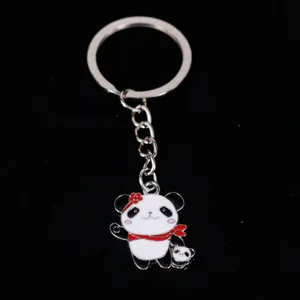 Close-up of a cute metal panda keychain with red scarf on black background