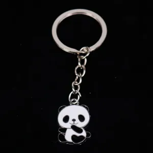 Close-up of a cute panda enamel metal keychain on a black background