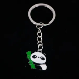 Detailed macro view of a cute metal panda charm with green bamboo on black background.