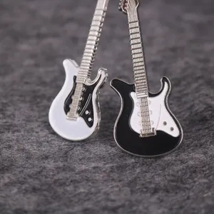 Primer plano de dos dijes de esmalte para guitarra eléctrica en miniatura blanco y negro