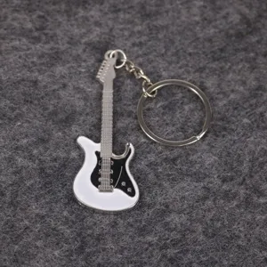 Primer plano de un llavero de guitarra eléctrica blanca con cuerdas y golpeador.
