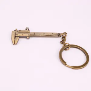 Llavero de mini calibre vernier vintage color bronce sobre un fondo blanco neutro