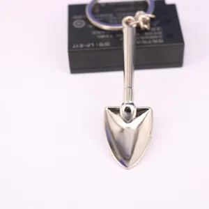Detalle de un llavero creativo con forma de mini pala de metal plateado pulido