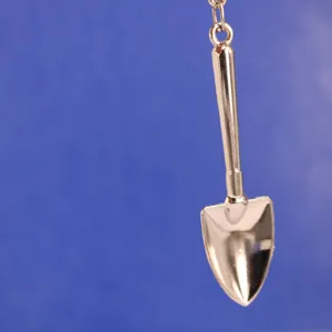 Imagen detallada de un llavero miniatura de metal plateado pulido en forma de pala.
