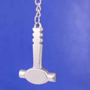 Vista detallada de un llavero creativo de metal plateado con forma de martillo pulido