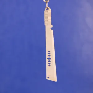 Primer plano de un llavero de metal plateado con forma de machete y detalles calados