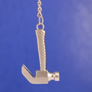 Primer plano detallado de un llavero miniatura de martillo de orejas hecho de metal plateado.