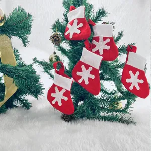 Decorative mini red Christmas stocking ornaments with snowflake design hanging on a tree.
