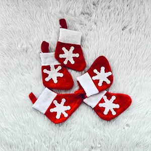 Detail view of five mini red Christmas stockings with white snowflakes on white faux fur rug.