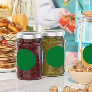 Close-up of circular green self-adhesive labels applied to glass jam jars