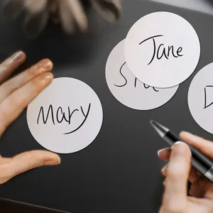 Detailed view of hand-written names on white round self-adhesive labels for organization