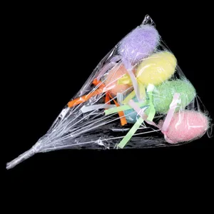 Detailansicht von fünf bunten glitzernden Osterai-Blumensteckern in Plastikverpackung.