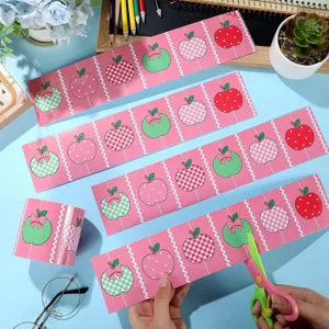 Détail de la découpe de bordures autocollantes roses à motif pommes pour tableau.