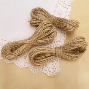 Dettaglio di tre mazzi di spago di iuta marrone naturale su un centrino bianco DIY