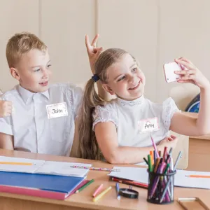 Kids pink bow self-adhesive name labels for school clothes and supplies classroom scene.