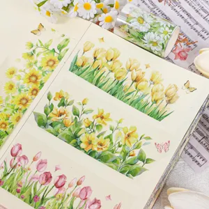 Nahaufnahme von bunten Aquarell-Blumen-PET-Aufklebern auf einem Notizbuch mit Vintage-Requisiten.