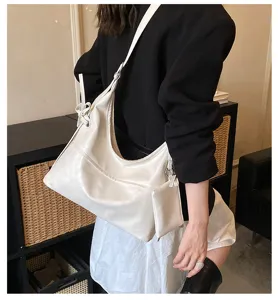 Bolso hobo minimalista de piel suave blanca con estuche a juego mostrado en un modelo