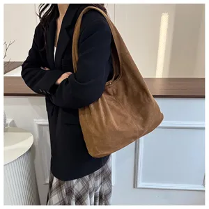 Vue détaillée d'un grand sac hobo en daim marron porté à l'épaule par un mannequin de mode