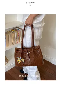 Nahaufnahme einer braunen geflochtenen Ledertasche mit einem Palmen-Anhänger