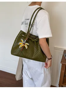 Seitenansicht eines Modells mit einer grünen gewebten Leder-Tote-Bag und Anhänger